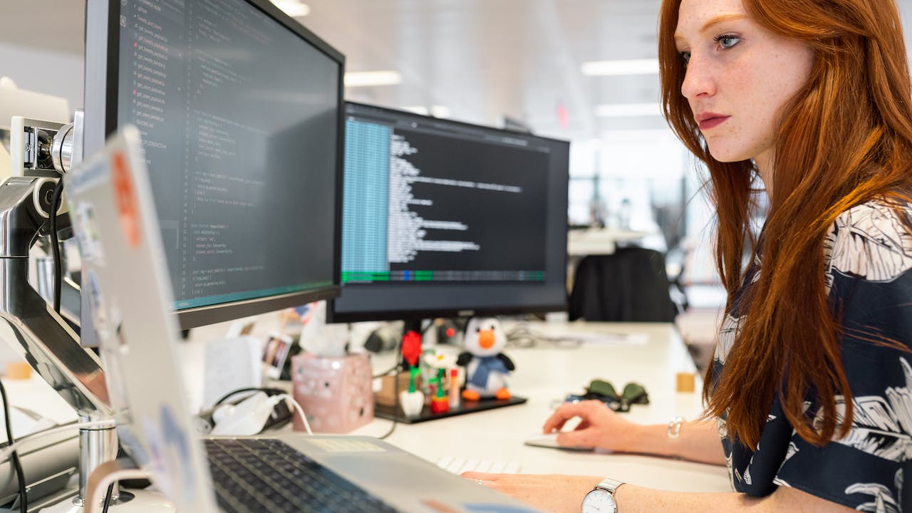 Female cybersecurity expert monitoring multiple screens to show what is SOC 2