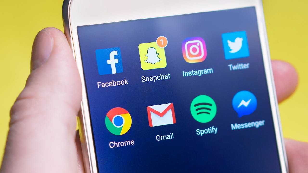 Employee holding cellphone with social media apps on home screen