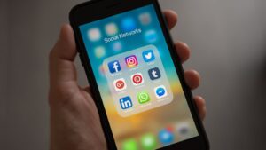 Employer holding cellphone with social media apps on screening depecting best practices for social media screening at work