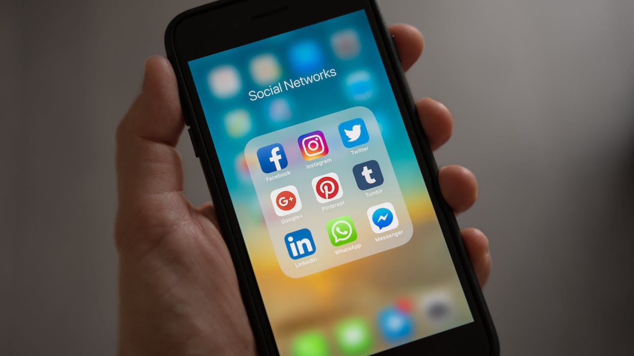 Employer holding cellphone with social media apps on screening depecting best practices for social media screening at work