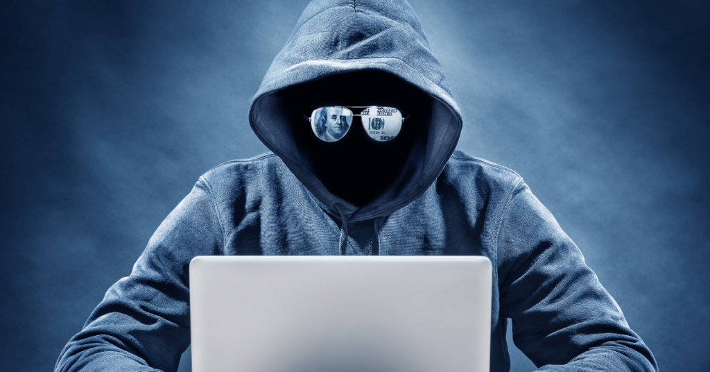 Person with Mask and Sunglasses on Computer Committing Fraud