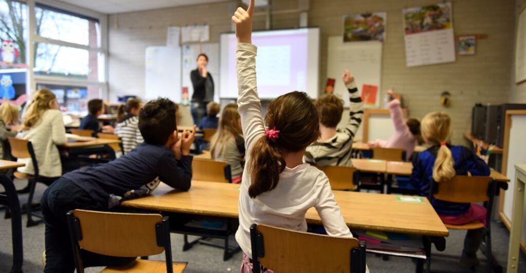 Educator with a teacher background check at front of busy classroom teaching students