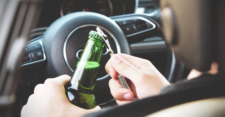 Open alcohol bottle behind wheel of car to show does a DUI show up on a background check