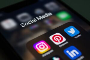 Smartphone screen displaying popular social media apps, highlighting the role of social media background checks in hiring practices