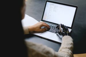 TA leader on laptop with one robotic hand depicting how AI is used in Certn background checks